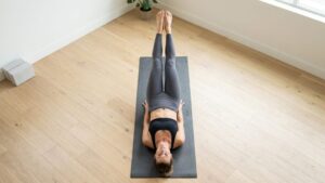 Leg raises exercise with hands under hips and lower back flat on mat correct form
